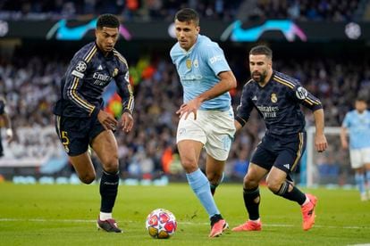 Rodri conduce el balón entre  Bellingham y Carvajal.